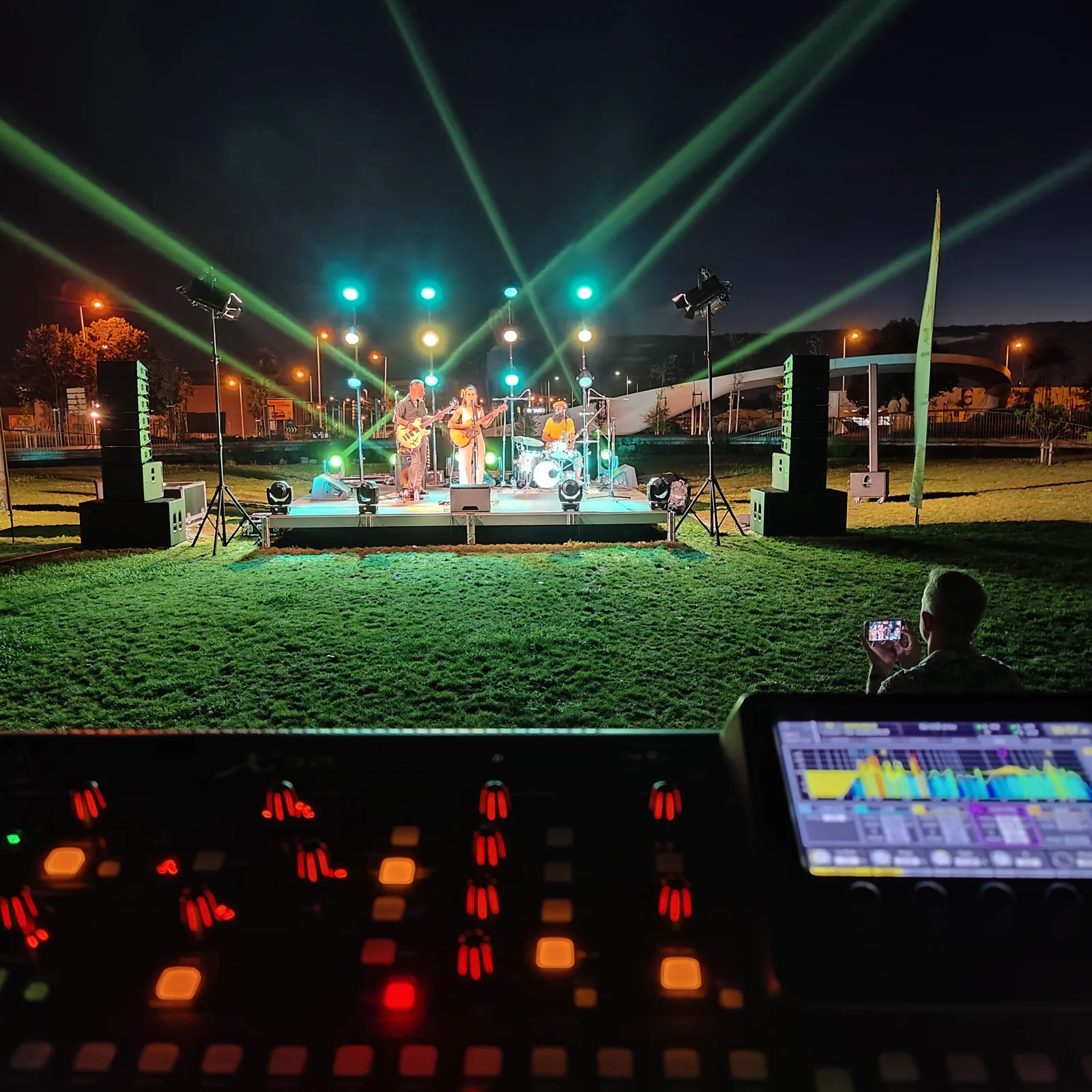 Mesa de iluminação e feixes de luz verdes sobre um palco ao ar livre